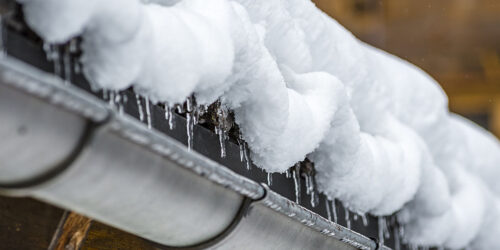 Snow on a wooden roof thawing in small ice cones